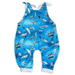 The front side view of Baby Blue by Cool Blue Maui’s Swim with Dolphins Romper which has an ocean blue background with grey swimming dolphins and a white with black polkadot cuff.