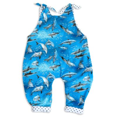 The front side view of Baby Blue by Cool Blue Maui’s Swim with Dolphins Romper which has an ocean blue background with grey swimming dolphins and a white with black polkadot cuff.
