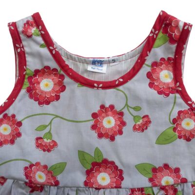 Close up view of the tank-top style top of a Baby Blue by Cool Blue Maui’s Red Vines Dress in a size 5 which has a soft grey background with red peony flowers and vines and red with white flowers trim and ruffle.
